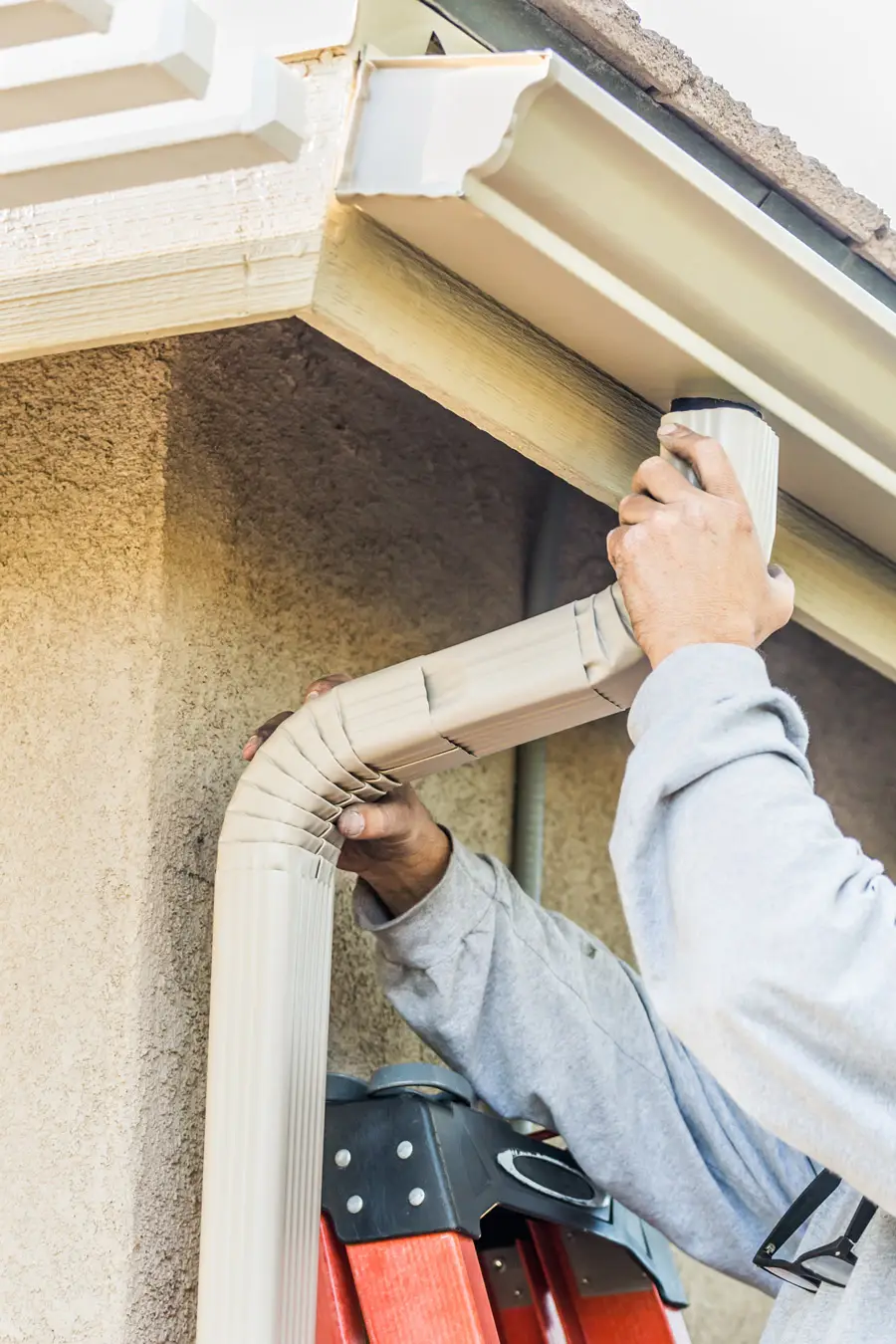 Hands of worker installing a gutter down spout.