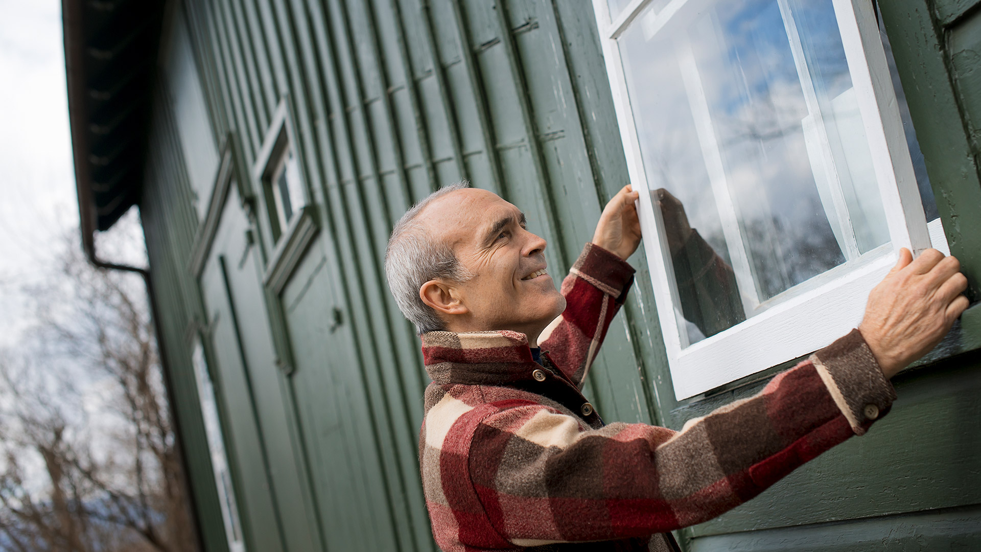 Man putting a window on the exterior of a house.