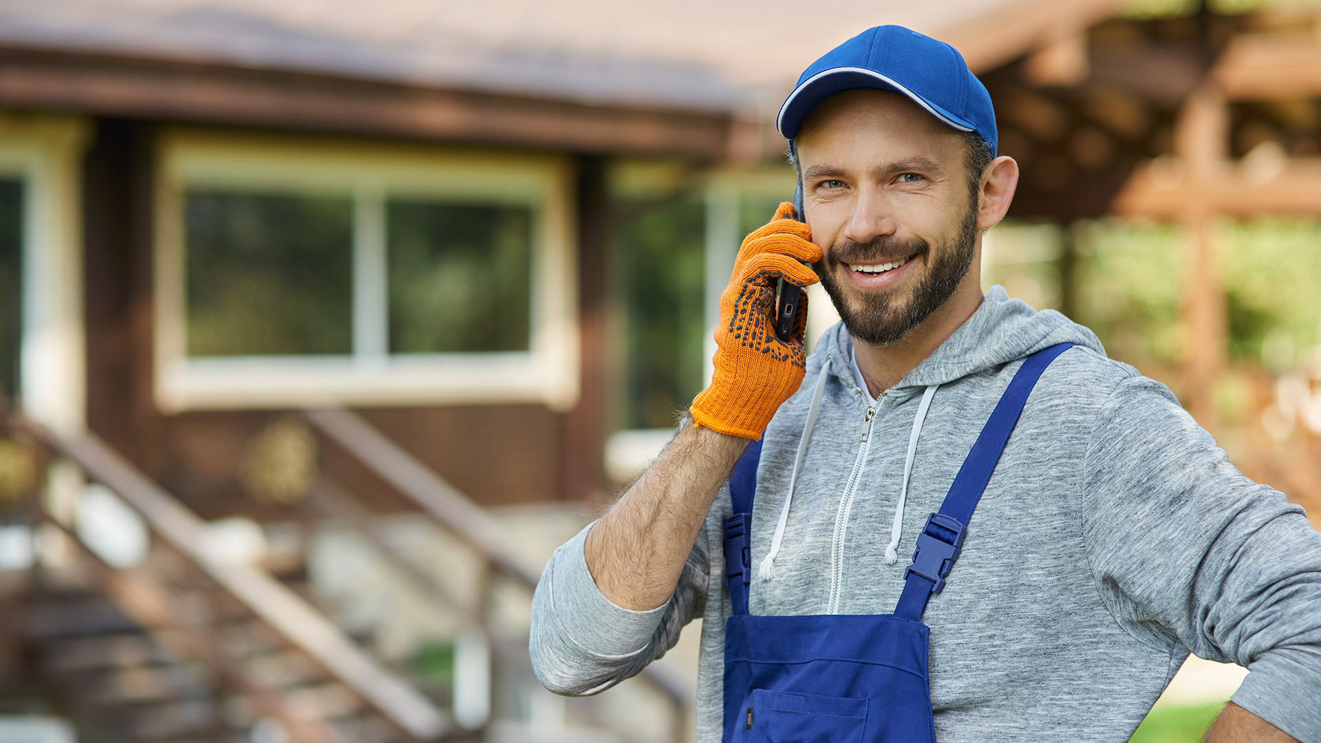 Siding contractor in work cloths on a phone with a customer.
